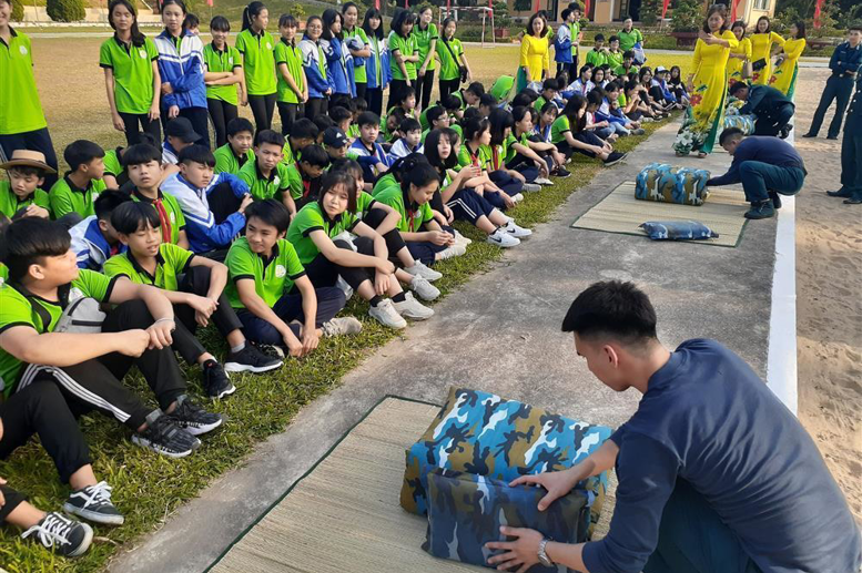Các chú bộ đội hướng dẫn học sinh gấp chăn màn