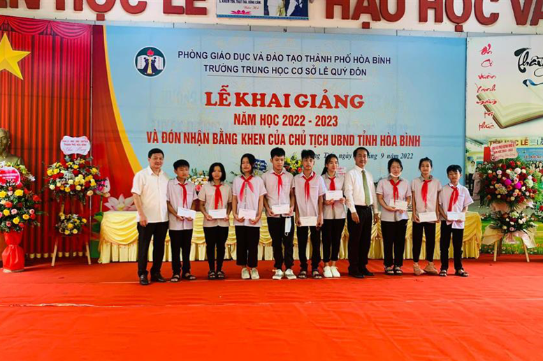 ông Lê Văn Thành - Ủy viên Ban Chấp hành Đảng bộ thành phố – Chủ tịch UBND phường Đồng Tiến, ông Nguyễn Văn Duấn – Trưởng Ban đại diên CMHS nhà trường - trao quàcho các em học sinh vượt khó vươn lên trong học tập