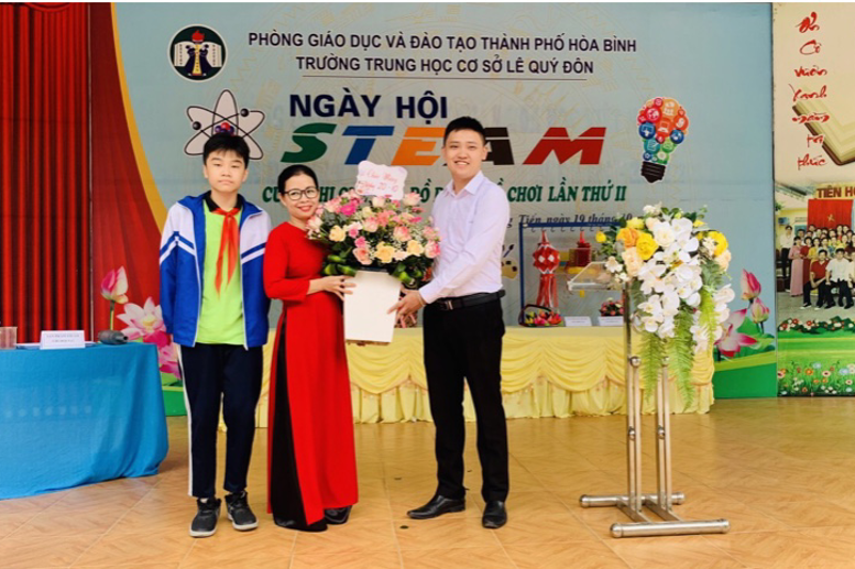 Thầy Bùi Huy Hoàng và em Nguyễn Anh Tuấn lớp 8A4 tặng hoa cho các cô giáo và các em học sinh nữ trong nhà trường.
