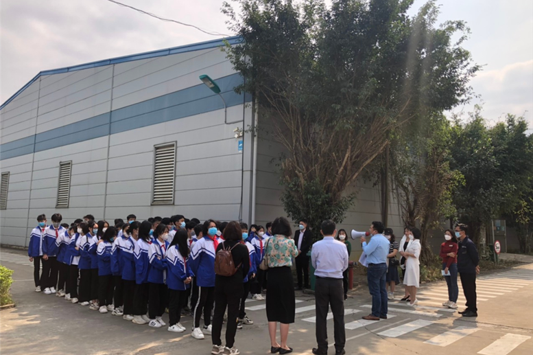 Các em học sinh xếp hàng, chăm chú lắng nghe các cô chú phổ biến về các quy định khi vào thăm quan nhà máy.