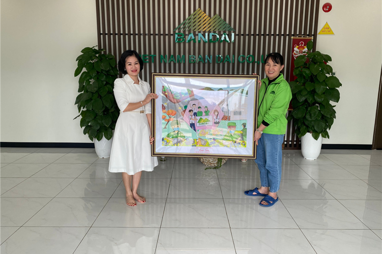 Cô giáo Phạm Thị Thu Hằng trao tặng bức tranh cho đại diện nhà máy
