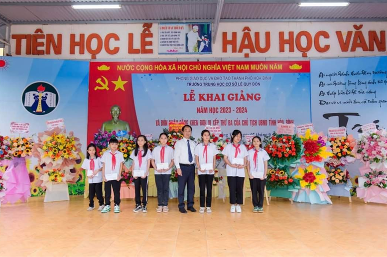 Ông Lê Văn Thành - Phó bí thư Đảng bộ Phường Đồng Tiến, Chủ tịch UBND Phường Đồng Tiến lên trao các phần quà, kinh phí hỗ trợ HS khó khăn của UBND phường Đồng Tiến và UBND phường Tân Thịnh cho các em HS có HCKK